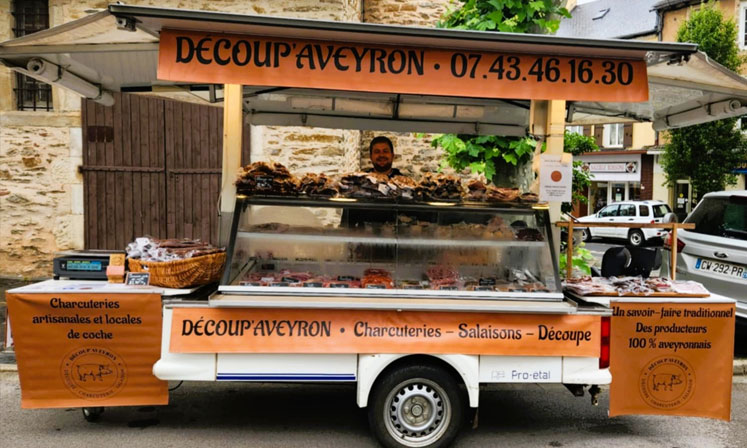 Photo du stand de vente mobile Découp'Aveyron avec le commerçant dans son stand.